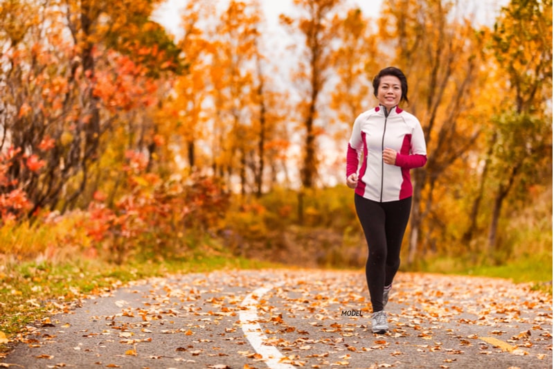 Asian woman jogging in the park during the fall