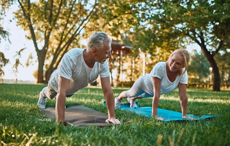 Older couple doing yoga together in the park