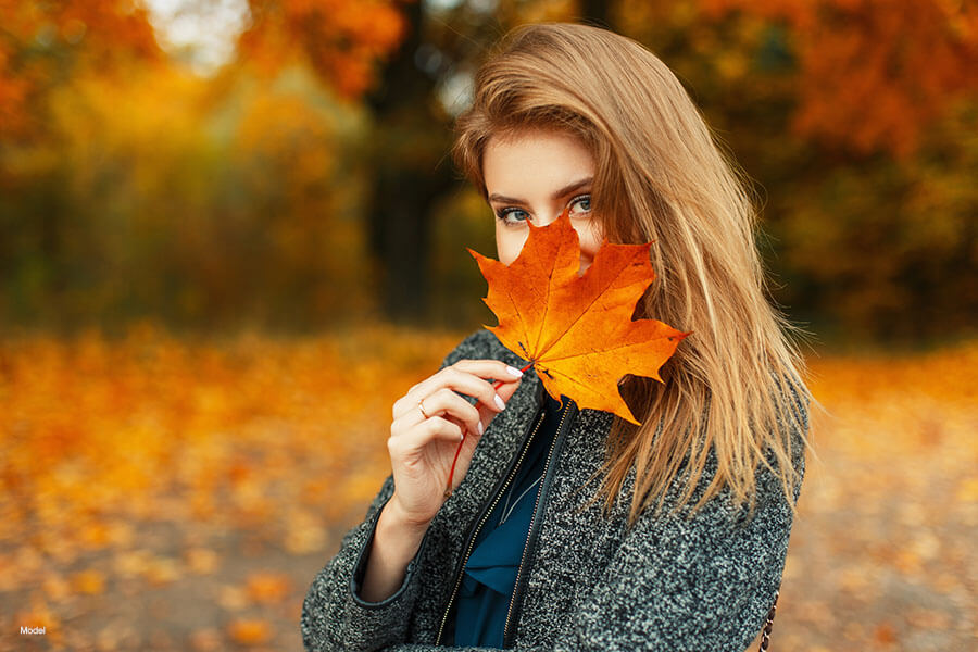 Woman holding a leaf over her face